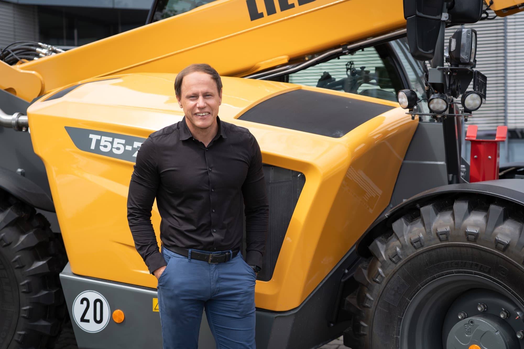 Dominik Märkl, CEO of OneStop Pro, in front of a Liebherr telehandler